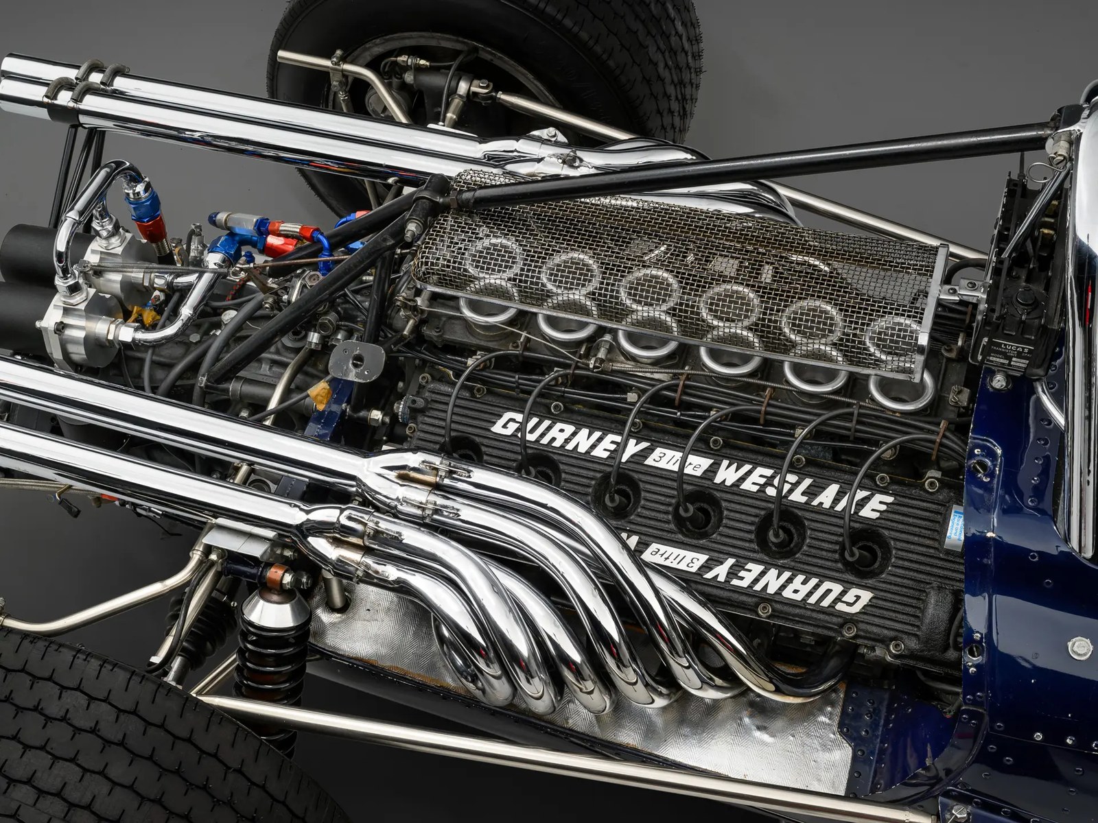 The Gurney-Weslake V-12: twelve individual intake trumpets under a mesh screen, cam covers cast with GURNEY on one bank and WESLAKE on the other, and the chromed header stack that made the car sound like nothing else on the 1967 grid.