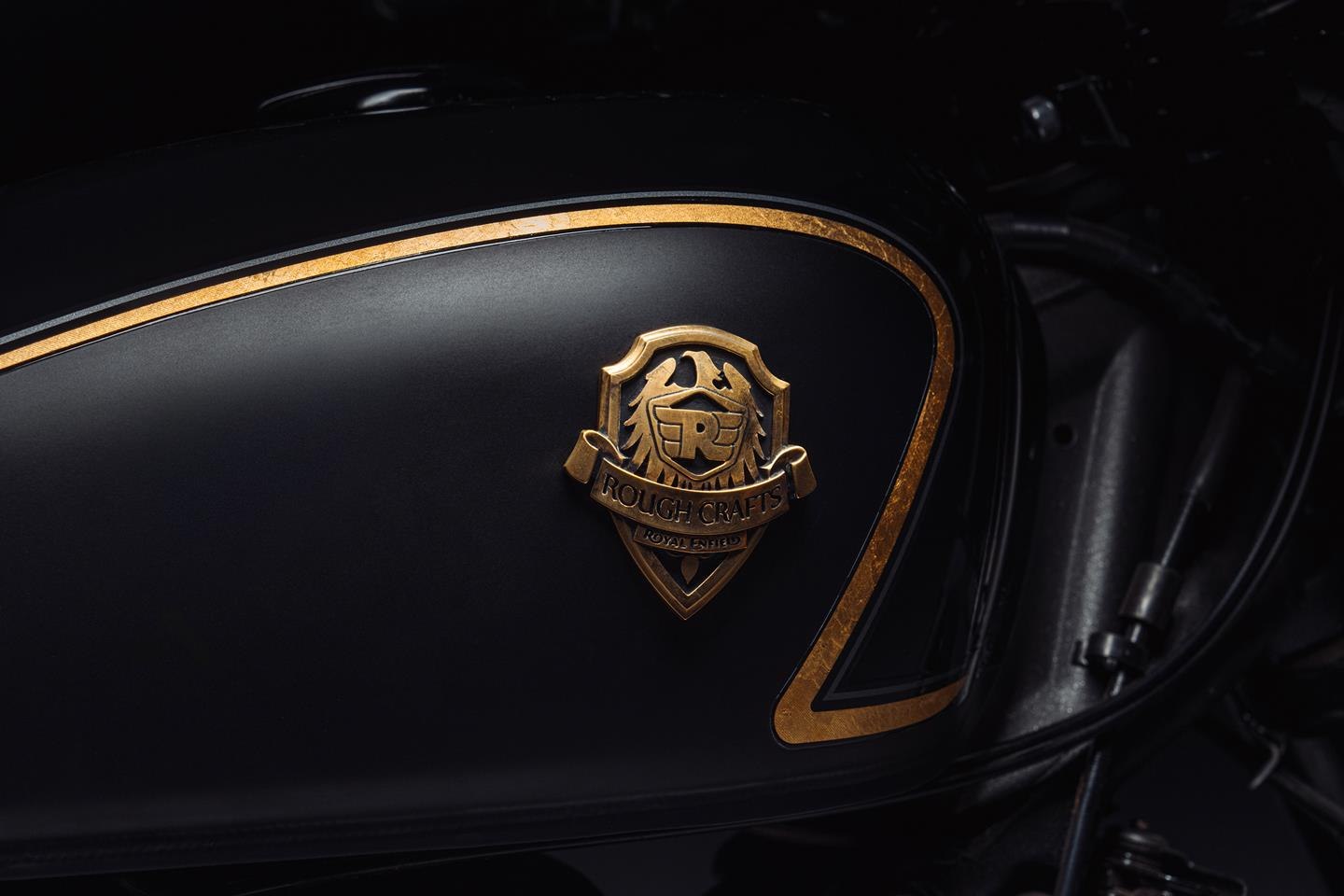 The cast-brass Rough Crafts collaboration badge on the tank, set into hand-applied gold-leaf pinstriping — one of the details carried over from Winston Yeh's original one-off Caliber Royale build.